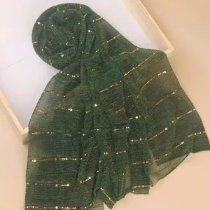 Close-up of dark green pleated scarf with gold sequins, lightweight textured fabric detail.