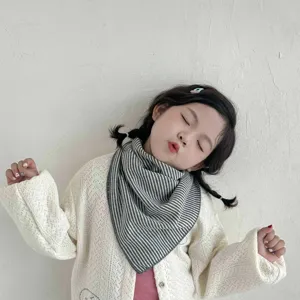 Detail shot of a cute child wearing a stylish grey and white striped triangular baby scarf.