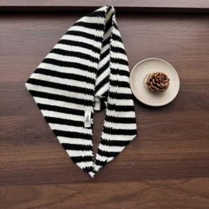 Close-up detail of black and white striped knit triangular scarf with cute small tag.