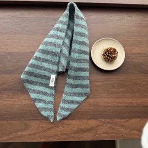 Detailed view of children knitted striped scarf in blue-green and grey with a cute tag.