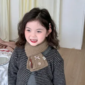 Cute knitted kids scarf detail, warm winter neck warmer with bow and button, soft toddler wear.