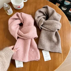 Detailed shot of cozy winter solid knit scarves in pink and taupe, soft textured everyday wear.