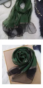 Close-up detail of the elegant green and black gradient silk scarf with shimmering gold stripes.