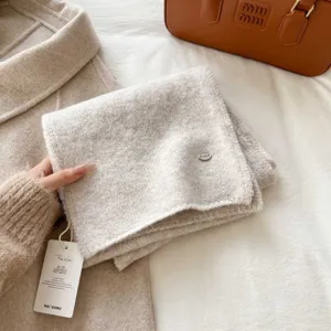 Knit scarf detail view showing soft knit texture and brand tag, premium fall winter accessory.