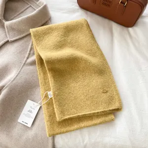 Cozy yellow knitted winter scarf with metal charm detail, soft wool texture warm neck wrap for women.