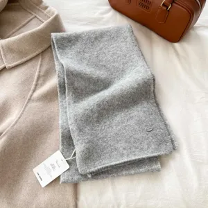 Grey knitted scarf detail, soft and warm winter accessory flat lay with clothing and bag prop.