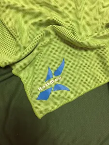 Gros plan détaillé de la serviette de sport rafraîchissante jaune-vert fluo en tissu mesh.
