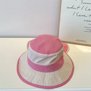 Close-up detail of the pink and white colorblock bucket hat with wide brim and sun cape.