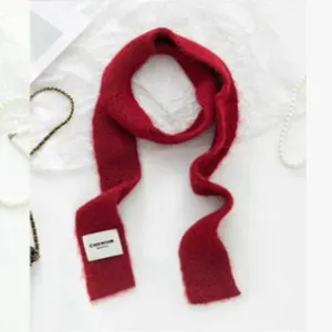 Detailansicht eines weichen, roten, schmalen Strickschals für herbstliche und winterliche Tage.