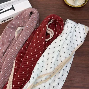 Detailed shot of retro pleated polka dot scarves in pink, red, and white on wood table.