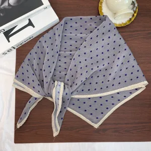 Detailed view of pleated polka dot square scarf with contrast border and blue dots on grey.