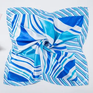 Close-up detail of the blue and white striped square silk scarf with elegant swirl pattern.