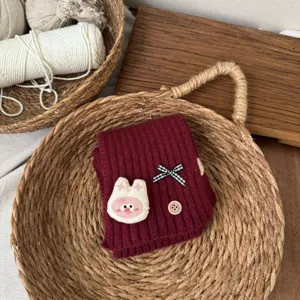Cozy children knitted neck warmer in deep red with cute rabbit patch and bow detail. Detail view.