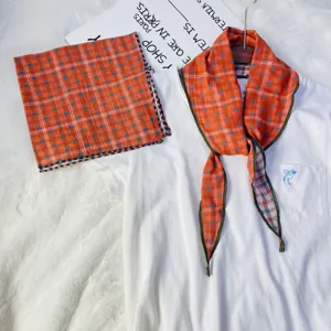 Close-up detail of the orange plaid cotton scarf and square kerchief set styled neatly.