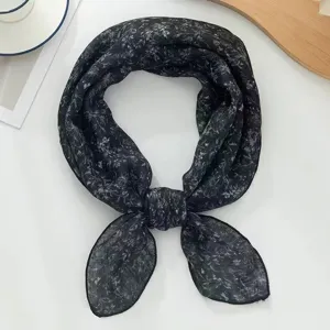 Nahaufnahme Detail eines schwarzen, floral gemusterten quadratischen Kopftuchs, Stoff.