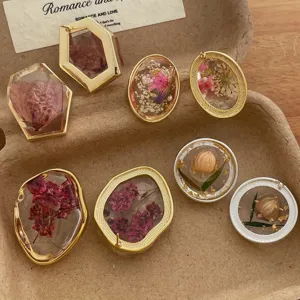 Detail shot of handmade resin geometric earrings featuring real dried flowers and gold flakes.