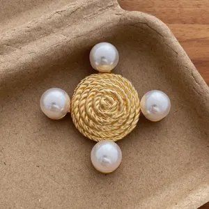 Vintage gold tone pearl brooch detail shot, elegant textured round brooch pin accessory.