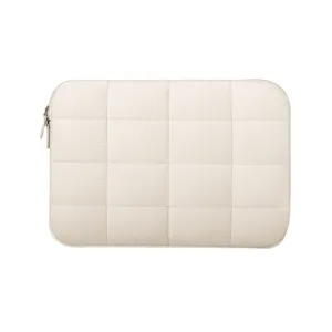 Detailed close-up shot of the beige quilted puffer laptop sleeve with soft grid pattern.