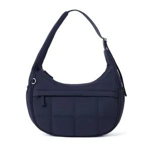 Dark blue quilted shoulder bag with soft puffy texture, front zip pocket and adjustable strap.