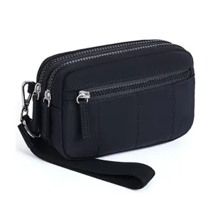 Close-up detail of the black nylon multi-zipper wrist bag, showing the durable hardware.