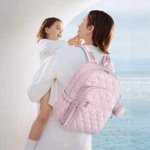 Primer plano de la mochila cambiador acolchada rosa llevada por una madre al aire libre.