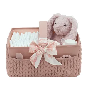 Panier organisateur de couches pour bébé matelassé rose avec nœud, couches et lapin peluche.