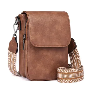 Close-up detail of the brown PU leather crossbody bag, featuring a patterned strap and zipper.