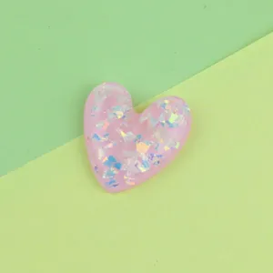 Pink resin heart charm with iridescent flakes, ideal for phone cases and DIY crafts.