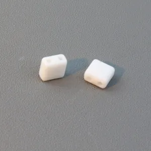 Close-up of white two-hole square acrylic spacer beads for DIY jewelry making accessories.