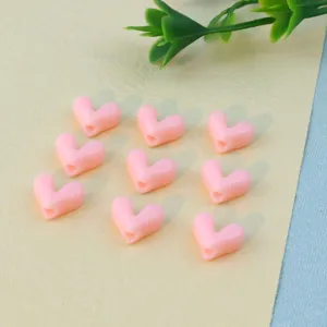 Close-up of pink heart-shaped loose beads with direct hole, perfect for DIY jewelry making.
