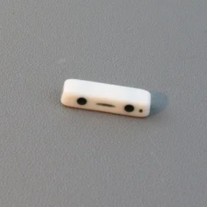 Detail view of a white double-hole acrylic spacer bead with cute face pattern for DIY jewelry crafts.