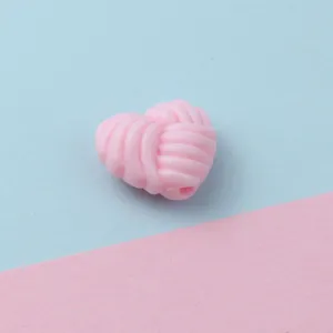 Pink twisted heart acrylic bead detail close-up view, cute DIY jewelry accessory for phone charms.