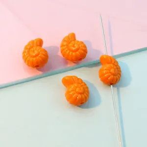 Close-up detail of orange conch shape acrylic beads with straight hole for DIY jewelry making.