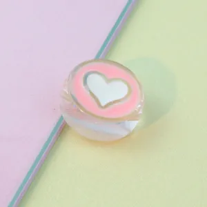 Close-up detail of transparent acrylic heart bead, pink oil drop craft, DIY accessory.