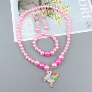 Close-up detail of cute pink pearl necklace bracelet and unicorn earrings set for kids.