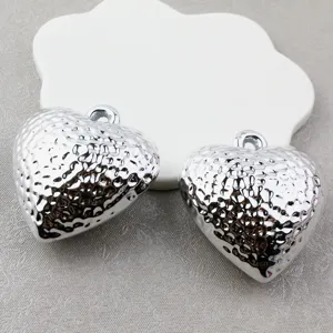 Close-up detail shot of silver hammered heart pendants with unique textured finish and loop.