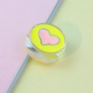 Close-up of 21mm transparent acrylic bead with neon green and pink heart oil-drop design.