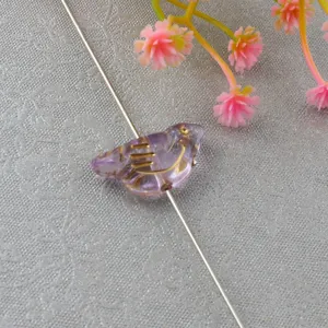 Detail shot of a purple acrylic bird bead with gold details, perfect for DIY jewelry making.