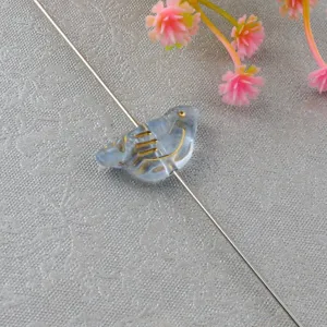 Close-up detail of a vintage gold-painted acrylic bird shaped loose bead for DIY jewelry making.