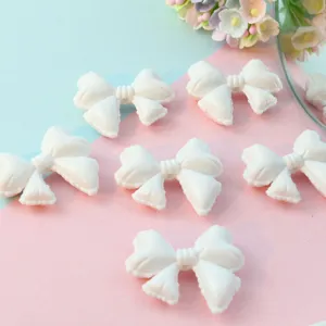 Detailed view of white acrylic bow loose beads, perfect for DIY phone charms and jewelry making.