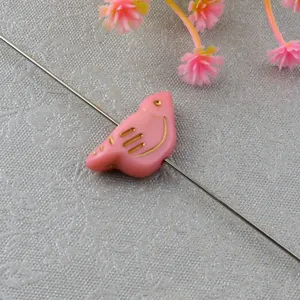 Pink acrylic bird loose bead detail shot, gold painted design, DIY jewelry crafting accessory.