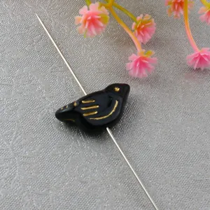 Detailed close-up of black gold-painted acrylic bird bead for DIY jewelry design.