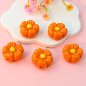 Detailed close-up of orange acrylic flower loose beads with yellow centers for DIY jewelry making.