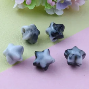 Close-up detail of black and white gradient acrylic star beads for DIY jewelry making.