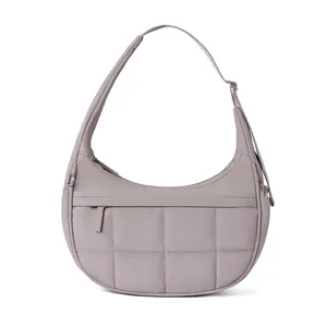 Detail view of the quilted puffer shoulder bag with adjustable strap and soft crescent shape.