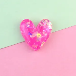 Close up of bright pink glitter heart resin charm detail, perfect for DIY phone case decor.