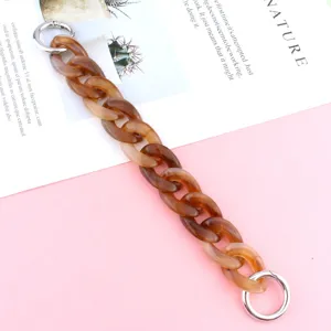 Amber style acrylic chain detail, resin bag strap link with silver metal rings, close up view.