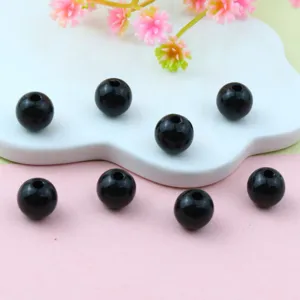 Close-up of glossy black round acrylic beads with center holes, ideal for DIY jewelry crafting.