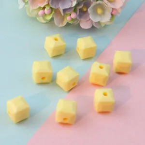 Detailed shot of yellow faceted square acrylic beads, perfect for DIY jewelry making and spacer use.