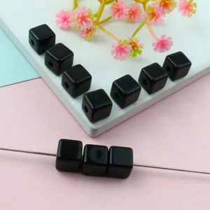 Detailed view of black square acrylic beads for DIY jewelry making and bracelet crafting.